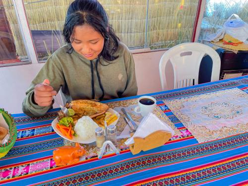 a woman sitting at a table with a plate of food at Lake View Lodge in Puno