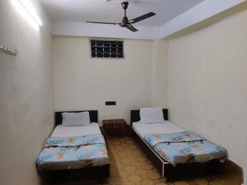 two beds in a room with a ceiling fan at HOTEL SUKHMANI in Guwahati
