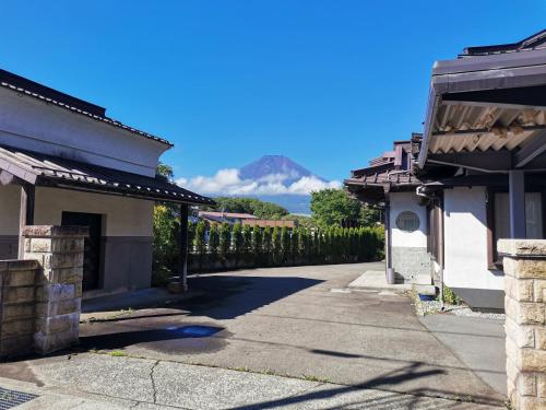 a road between two houses with a mountain in the background at 福寿苑　Fukujuen in Oshino