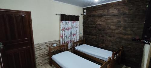 a room with two beds and a wooden wall at Melhor localização em Ilha Grande - 5min do cais in Abraão
