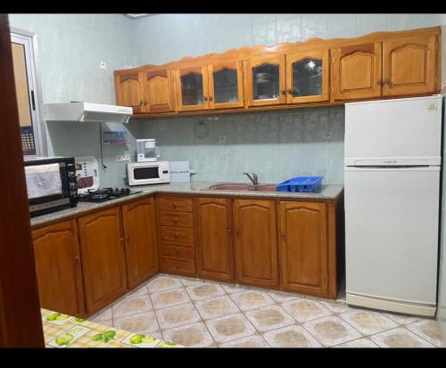 una cucina con armadi in legno e frigorifero bianco di apparemment carabonita a El Jadida