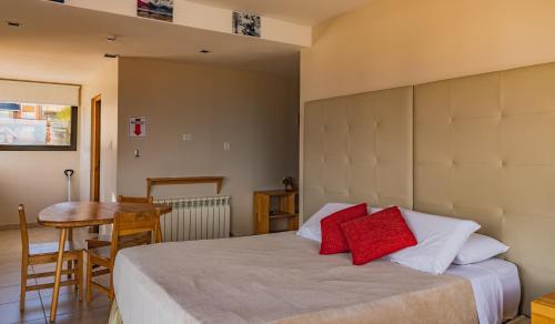 a bedroom with a bed with red pillows and a table at Miralejos in Ushuaia