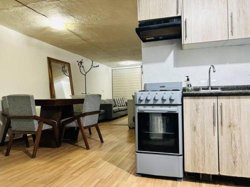 cocina y sala de estar con fogones y mesa en Cómoda casa con dos cuartos y cochera para auto pequeño, en Guadalajara