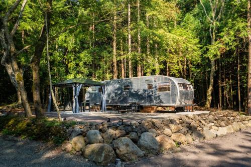 an rv parked in the middle of a forest at 本栖ベース～ヴィンテージトレーラーとバレルサウナ’1日1組限定’の貸切別荘～ in Fujikawaguchiko