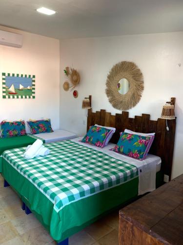 1 dormitorio con 2 camas y espejo en la pared en Maria Flor Pousada, en Taíba