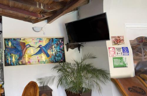 a flat screen tv on a wall with a painting at Hotel Randuky Tayrona in El Zaino