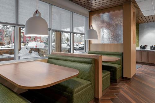 Fairfield by Marriott Inn & Suites Hailey Sun Valley في هايلي: مطعم ذو كراسي وطاولات ونوافذ خضراء