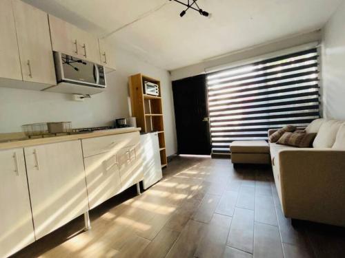 a kitchen and living room with a couch in a room at Cómodo y sencillo estudio bien ubicado in Guadalajara