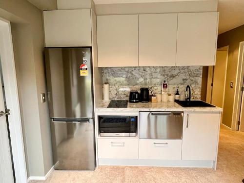 a kitchen with white cabinets and a stainless steel refrigerator at Garden Of Eden in Queenstown
