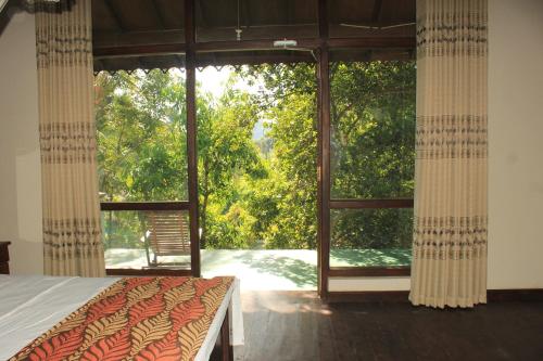 a bedroom with a bed and a large glass window at Serenity Sigiri Resort in Sigiriya