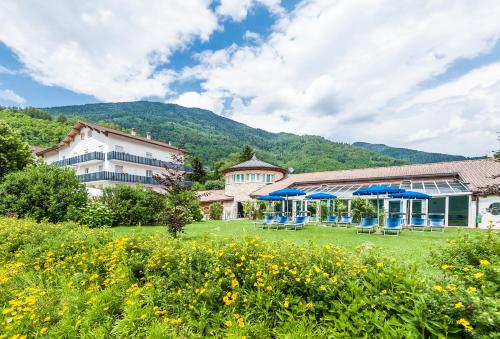a building with blue umbrellas in a field at Hotel Al Sorriso Greenpark & Wellness in Levico Terme