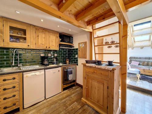 une cuisine avec des armoires en bois, un évier et une cuisinière dans l'établissement Appartement moderne mansardé Au pied des pistes Centre village - FR-1-344-860, à Saint-Martin-de-Belleville