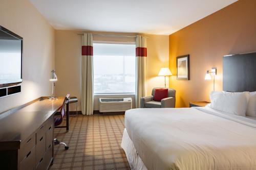 ニスクにあるFour Points by Sheraton Edmonton International Airportのベッド、デスク、窓が備わるホテルルームです。