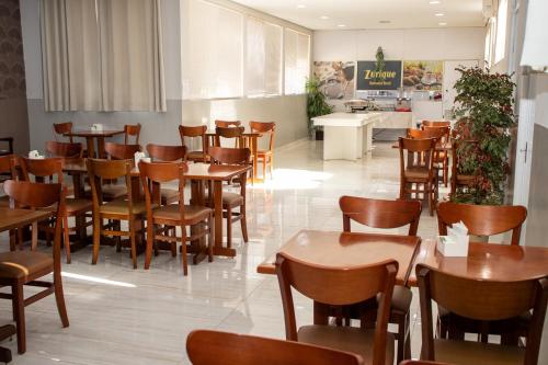 a dining room with wooden tables and chairs at Zurique Sorocaba Hotel in Sorocaba