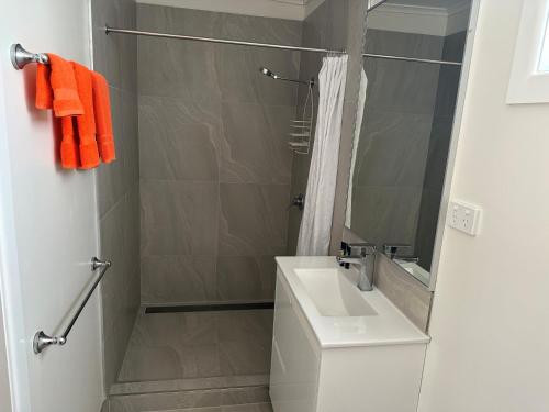 La salle de bains est pourvue d'un lavabo, d'une douche et de serviettes orange. dans l'établissement Winton Outback Motel, à Winton