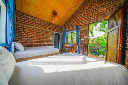 a bedroom with two beds and a brick wall at An An Homestay Bungalow in Phong Nha