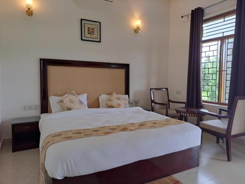 ein Schlafzimmer mit einem großen weißen Bett und einem Stuhl in der Unterkunft GREEN VALLEY SARISKA in Tehla