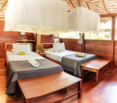 プエルト・マルドナードにあるEcolucerna Lodge Tambopataのベッドルーム1室(ベッド2台、ベンチ付)