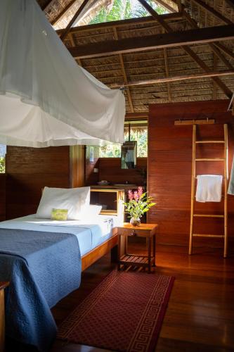 a bedroom with a bed and a ladder and a table at Ecolucerna Lodge Tambopata in Puerto Maldonado
