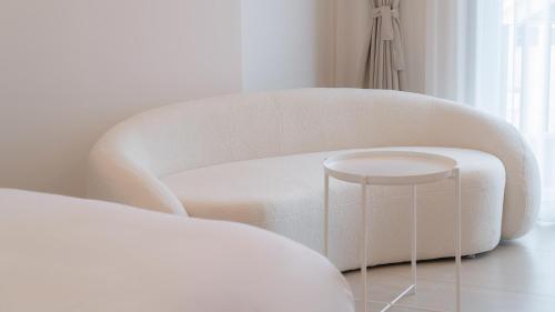a white chair and a stool in a room at Geoje Mongdol Beach H Avenue Hotel in Geoje 