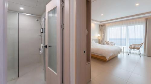 a bathroom with a shower and a bedroom with a bed at Geoje Mongdol Beach H Avenue Hotel in Geoje 