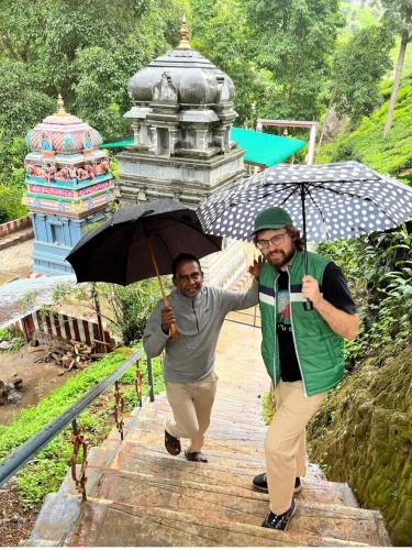 two men walking down the stairs with an umbrella at Narmada Holiday Home in Ooty