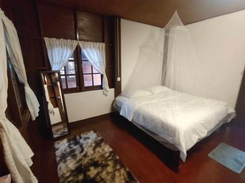 een slaapkamer met een wit bed en een raam bij เฮือนฮิมธารโฮมสเตย์ in Ban Pang Champi