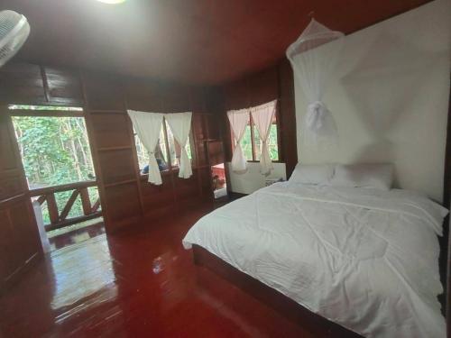 een slaapkamer met een bed met witte lakens en ramen bij เฮือนฮิมธารโฮมสเตย์ in Ban Pang Champi