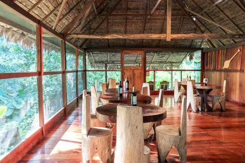 a restaurant with wooden tables and chairs and windows at Ecolucerna Lodge Tambopata in Puerto Maldonado