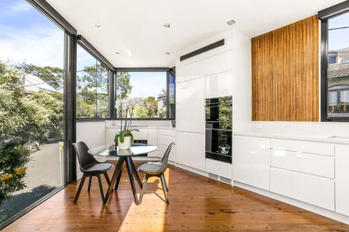 cocina con mesa y sillas y ventanas grandes en Woollahra house beautiful 3 bedroom terrace, en Sídney