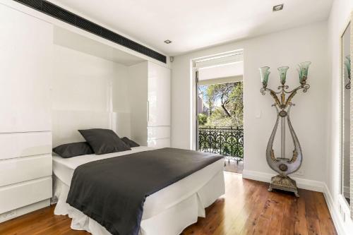 a white bedroom with a large bed and a window at Woollahra house beautiful 3 bedroom terrace in Sydney