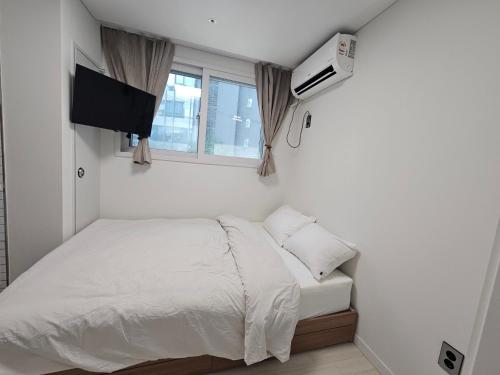 Dormitorio pequeño con cama y TV en Maison Apartment Residense, en Seúl