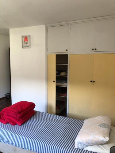 a bedroom with a bed with a red blanket and cabinets at Ordeig 2223 in Montevideo