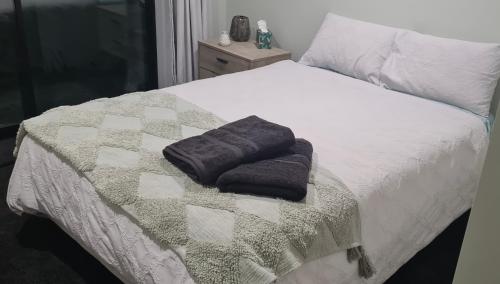 a bed with two towels sitting on top of it at Room With A view in Napier