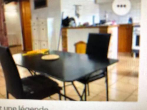 - une table à manger et des chaises noires dans le salon dans l'établissement F3 HOCHE 2 éme étage, à Coursan