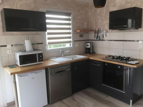 a small kitchen with a sink and a microwave at MAISON DE VACANCES 4 Clés - BORD DE MER DENNEVILLE PLAGE in Denneville