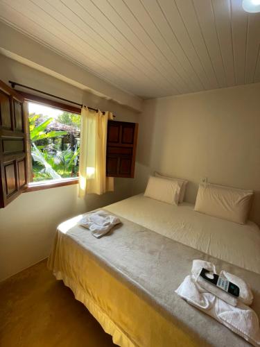 a bedroom with a large bed and a window at Pousada Jambrero in Caraíva