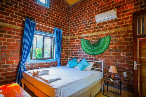 a bedroom with a bed in a brick wall at An An Homestay Bungalow in Phong Nha