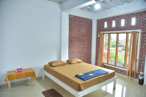 1 dormitorio con cama y pared de ladrillo en Toraja Dannari Homestay, en Rantepao
