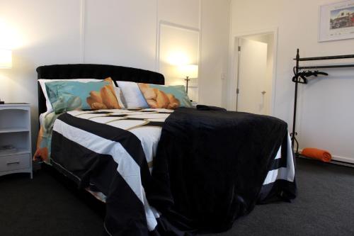 a bedroom with a black and white bed with pillows at The Pool House Bed & Breakfast - Napier in Napier
