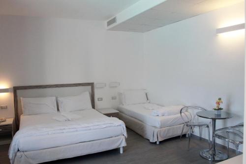 a hotel room with two beds and a table at Hotel Miramare in Marina di Ragusa