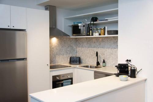 a kitchen with white cabinets and a counter top at #55highstreetauckland in Auckland