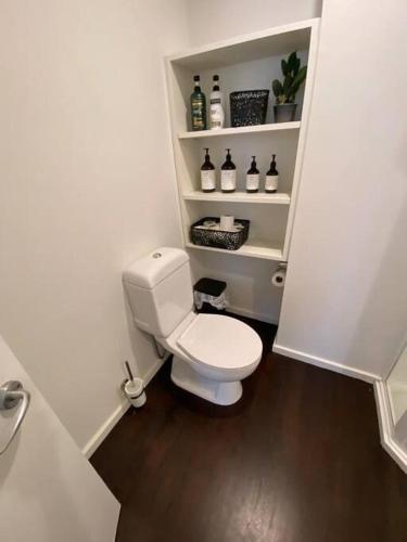 a small bathroom with a white toilet and shelves at #55highstreetauckland in Auckland