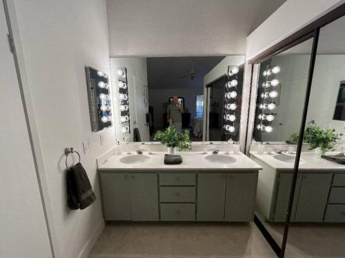 a bathroom with two sinks and a large mirror at Woodhaven Incredible Views on the Golf Course in Palm Desert