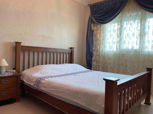 1 dormitorio con cama de madera y ventana en Appartement de standing calme en centre ville IMAZUR, en Tánger
