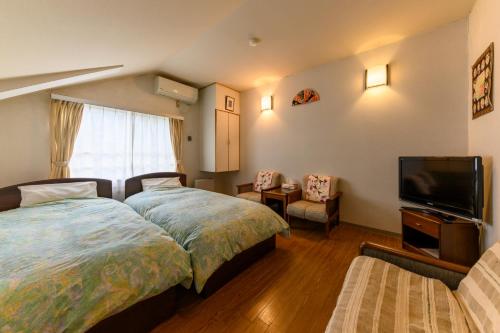 a bedroom with two beds and a flat screen tv at Fujiyoshi in Nozawa Onsen