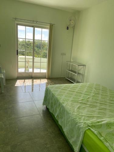 a bedroom with a green bed and a large window at Reshma appartement in Trou aux Biches
