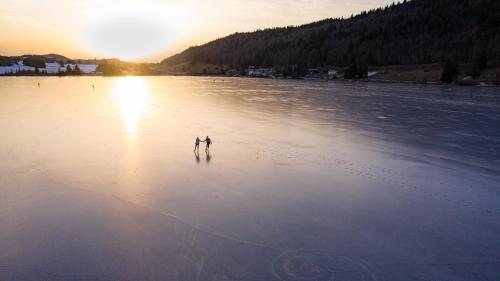 two people walking on a frozen lake at sunset at Appartement Les rousses, Jura in Les Rousses