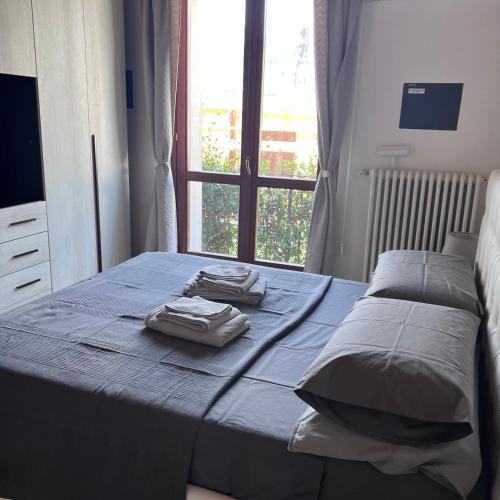 a bed with two towels on it in a room with a window at VILLA LIDO - Lake Como in Colico