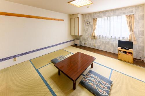 a living room with a table and a tv at Fujiyoshi in Nozawa Onsen